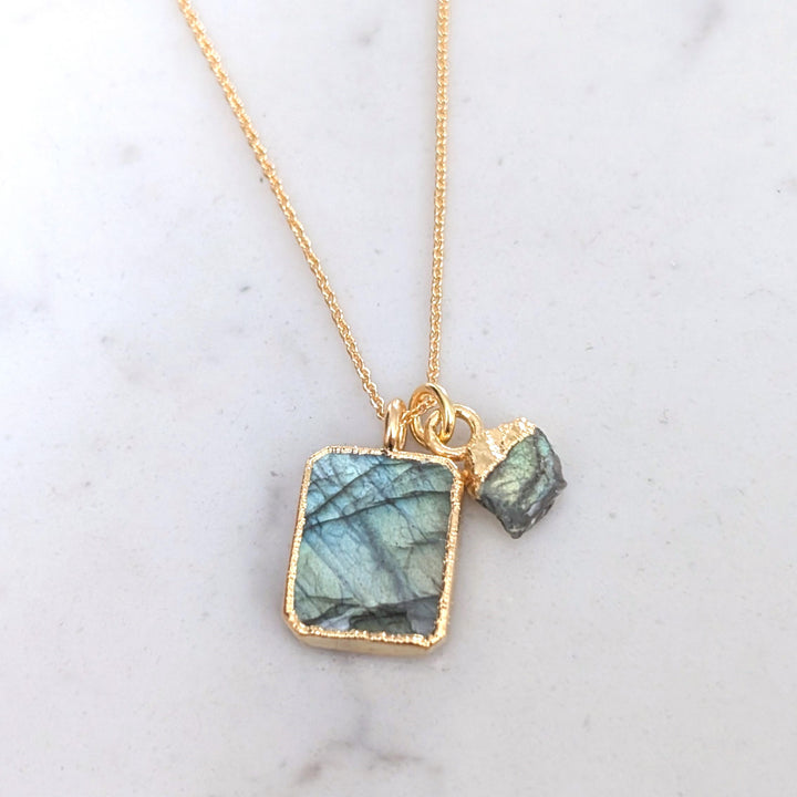 A gold-plated necklace featuring a rectangular labradorite pendant and a small labradorite tumblestone charm.