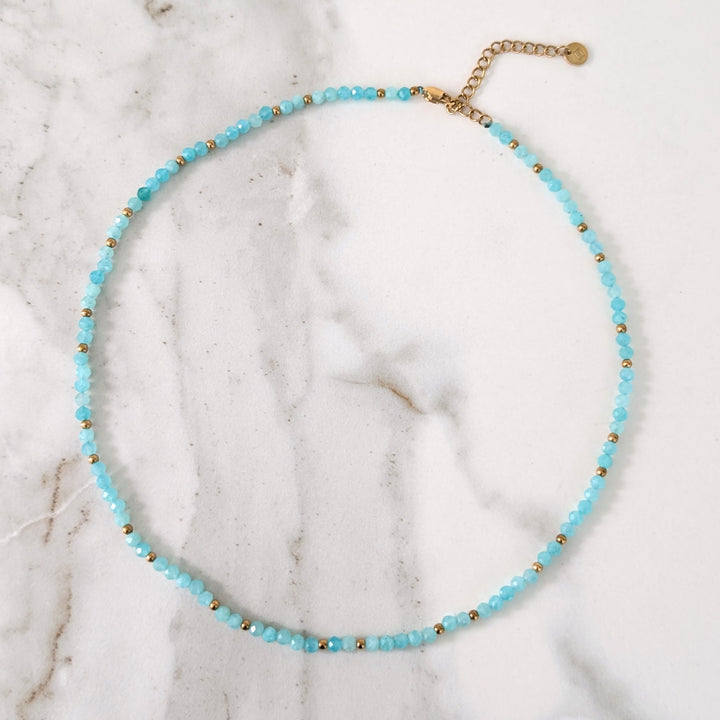 A delicate amazonite gemstone beaded necklace made of light blue faceted beads interspersed with gold beads.