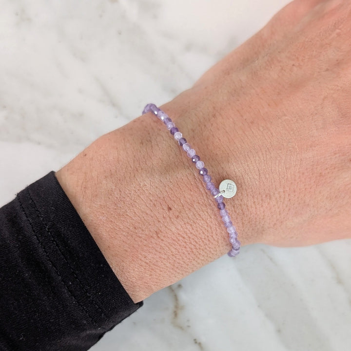 Purple 2mm beaded amethyst bracelet with a silver charm 