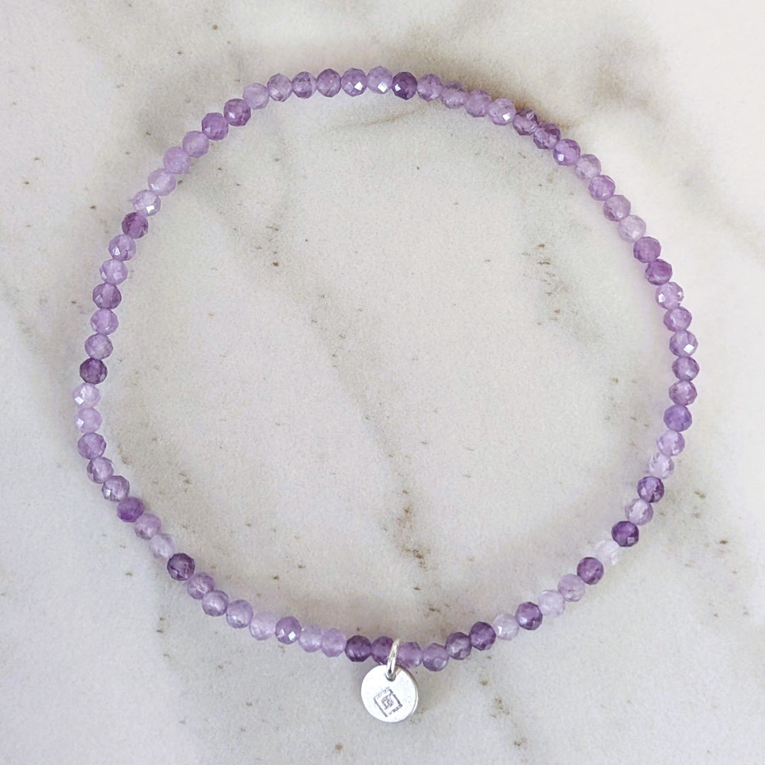 Purple 2mm beaded amethyst bracelet with a silver charm 