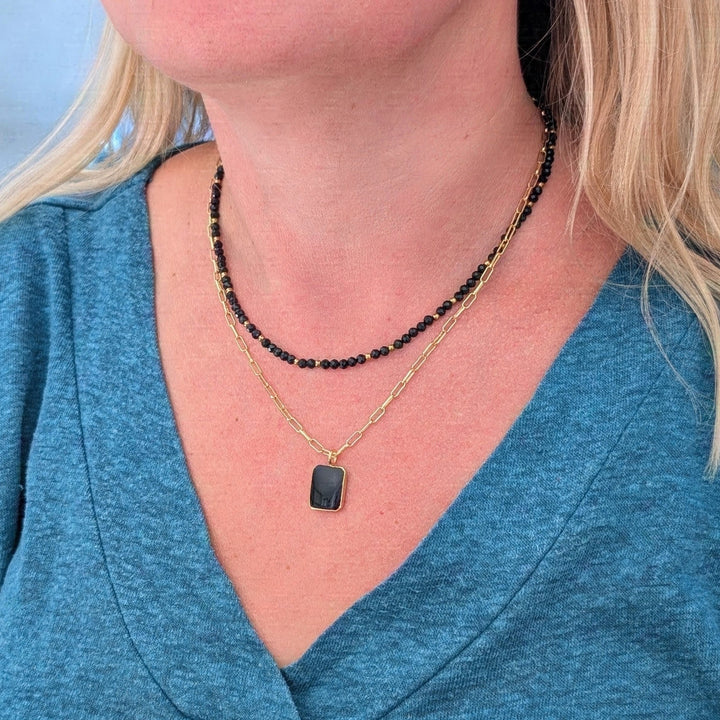 black tourmaline gemstone and gold bead faceted bead necklace layered with a gold black onyx rectangular pendant necklace