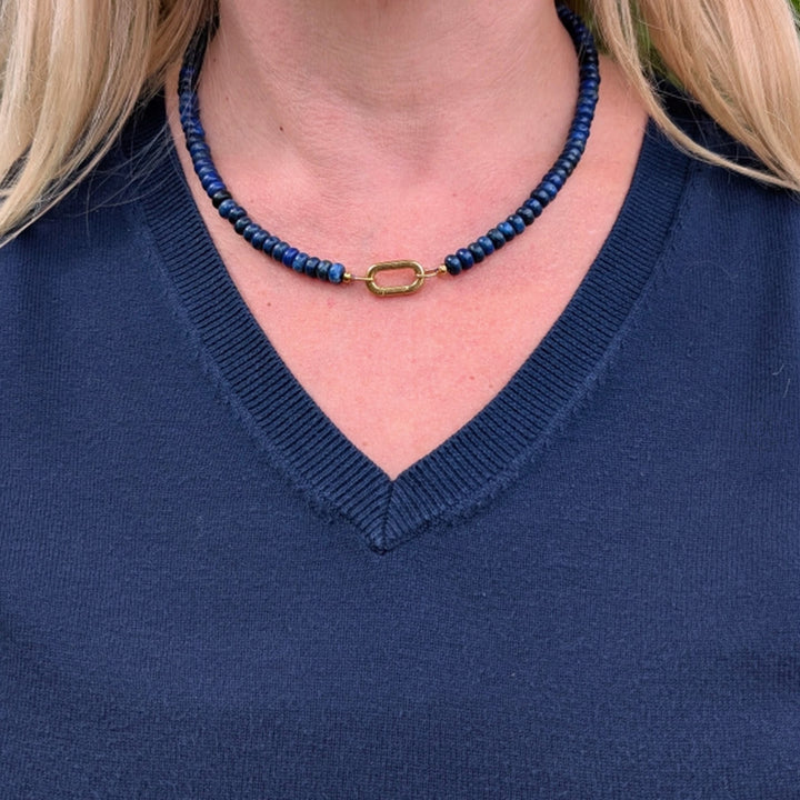 A gemstone beaded necklace made of blue lapis lazuli stones with a gold clasp.