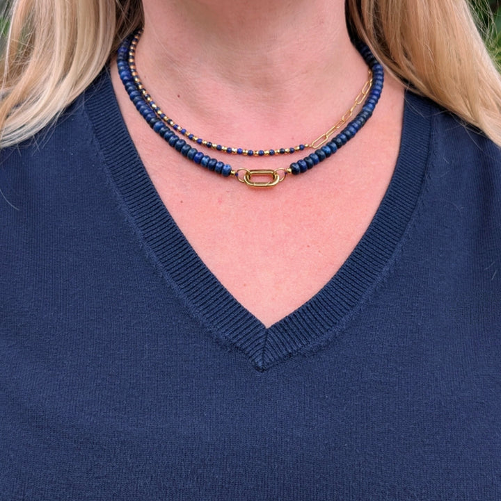A gemstone beaded necklace made of blue lapis lazuli stones with a gold clasp.