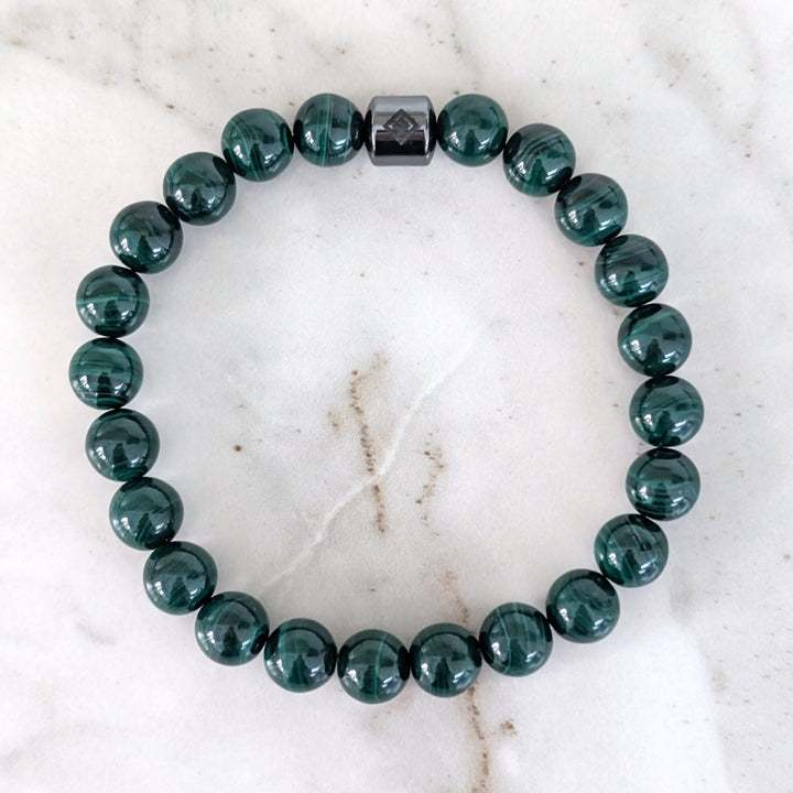 A men's 8mm beaded stretch bracelet made of polished dark green malachite beads with a single dark metallic hematite bead.