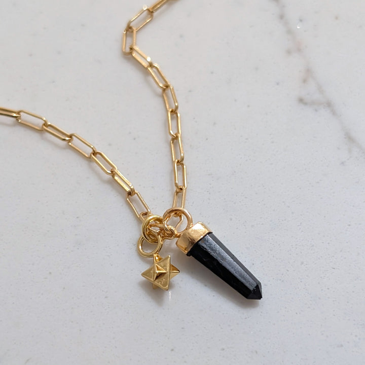 gold paperclip necklace with black tourmaline gemstone point pendant and tetrahedron star charm