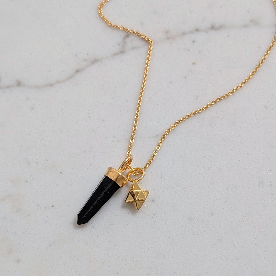 gold necklace with black tourmaline gemstone point pendant and tetrahedron star charm
