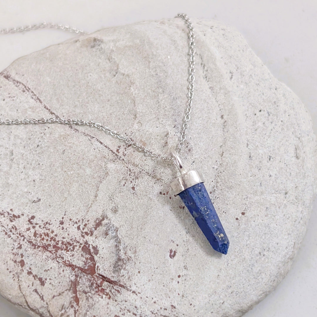 Blue lapis lazuli pendant gemstone necklace on a stone surface