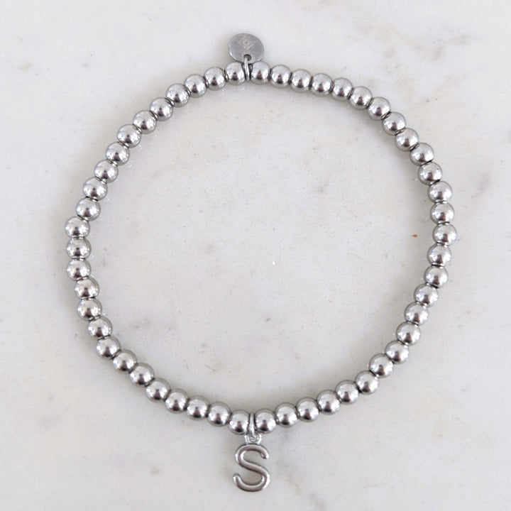A silver stainless steel PVD beaded stretch bracelet with alphabet letter charm.
