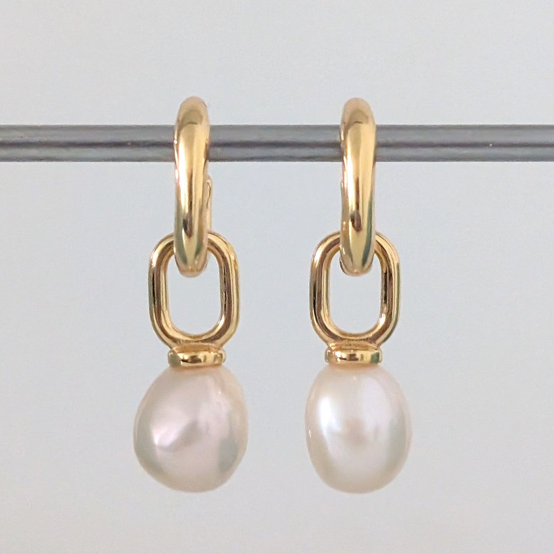a pair of gold pearl earring charms on  huggie hoops