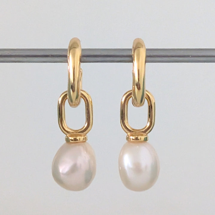 a pair of gold pearl earring charms on  huggie hoops