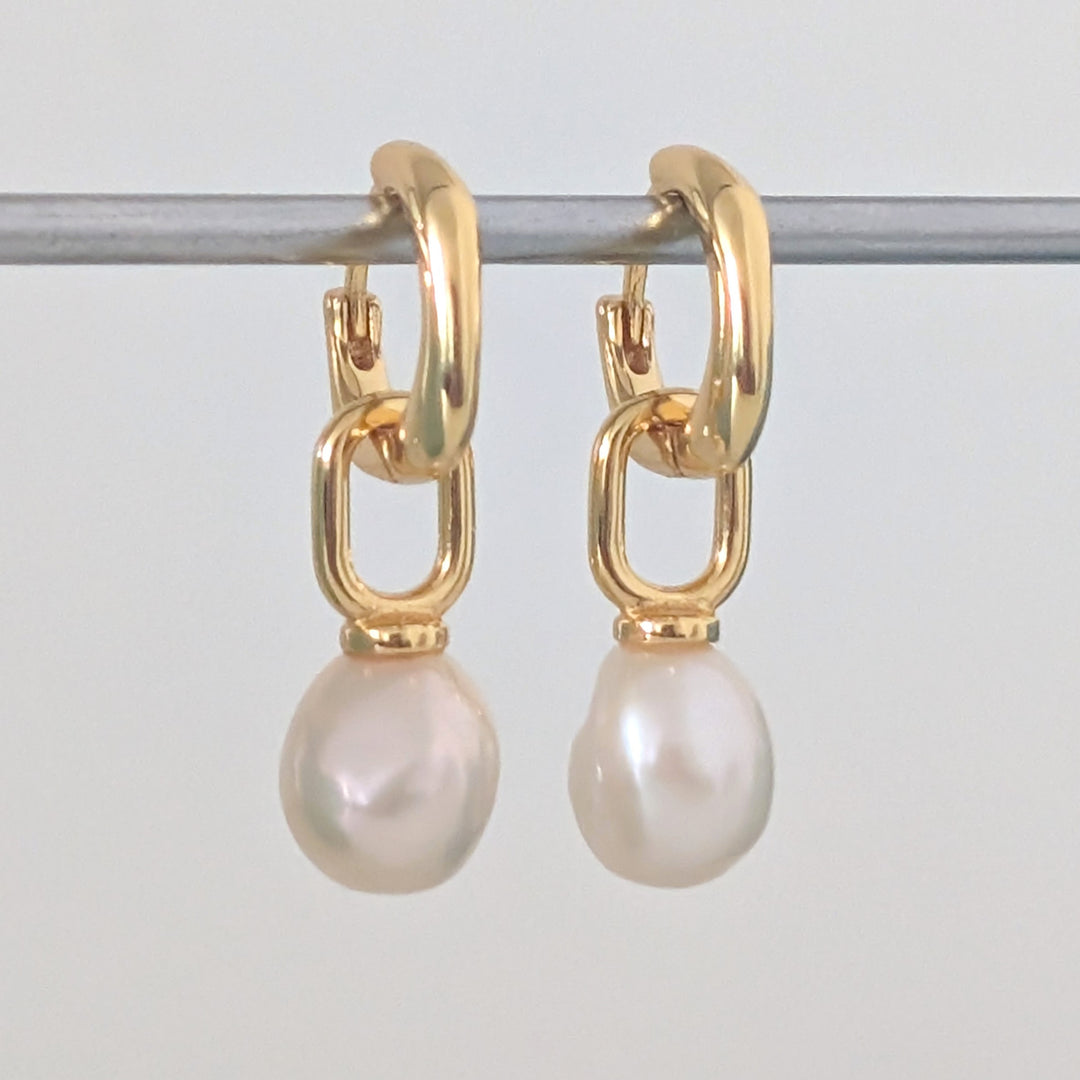 a pair of gold pearl earring charms on  huggie hoops