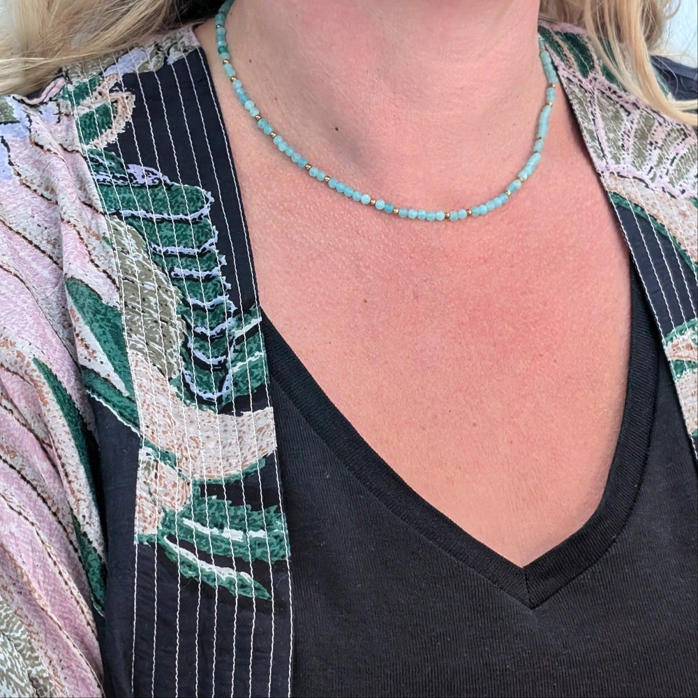 A delicate amazonite gemstone beaded necklace made of light blue faceted beads interspersed with gold beads.