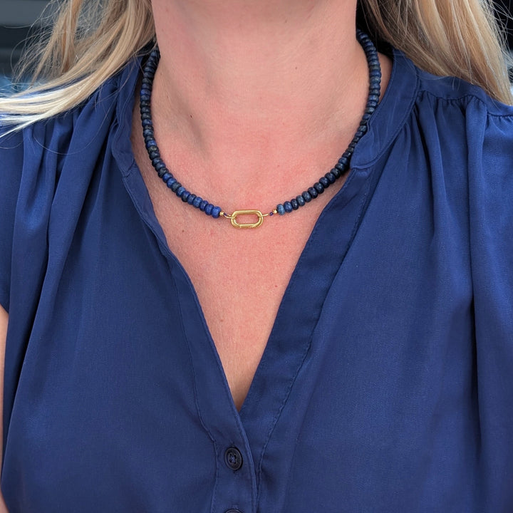A gemstone beaded necklace made of blue lapis lazuli stones with a gold clasp.
