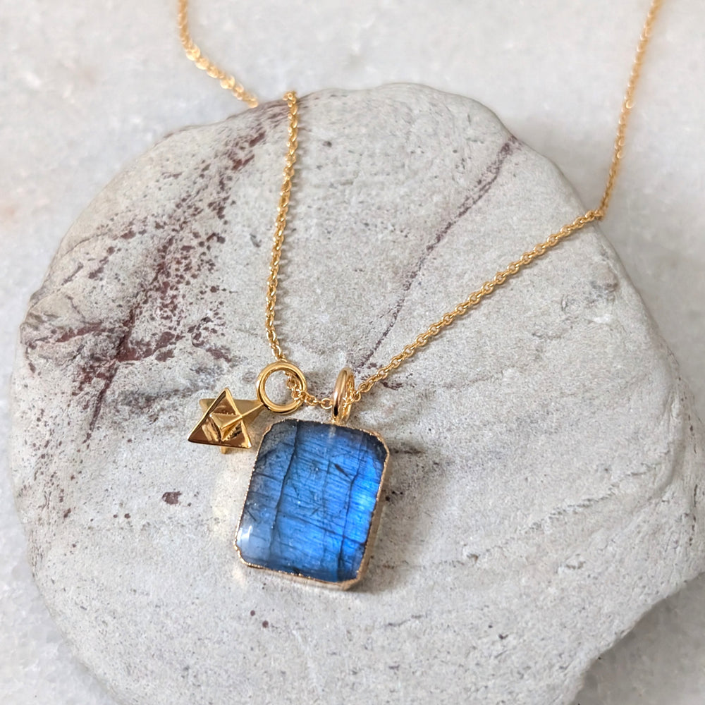 Gold necklace with a blue rectangular labradorite pendant and gold tetrahedron charm 