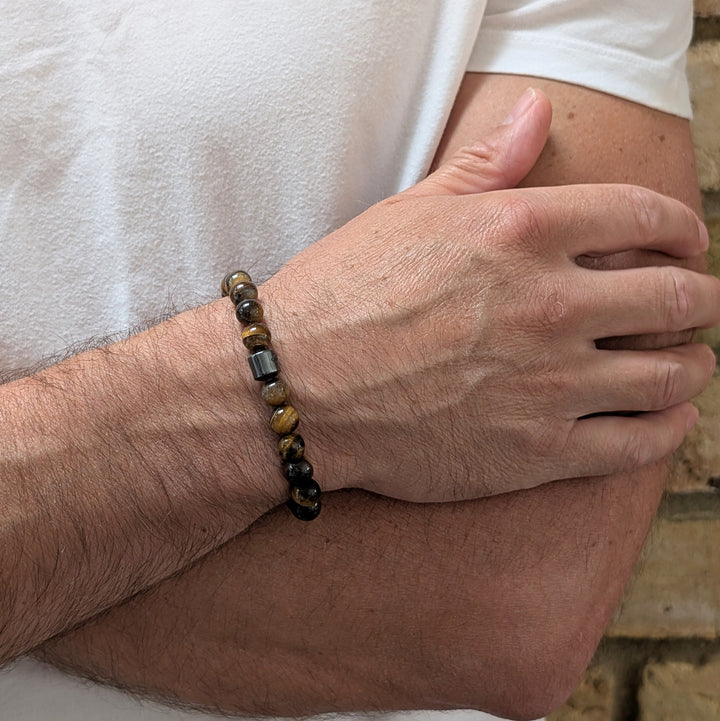 A 8mm beaded men's tiger's eye stretch bracelet with a single hematite Lapis London logo bead.