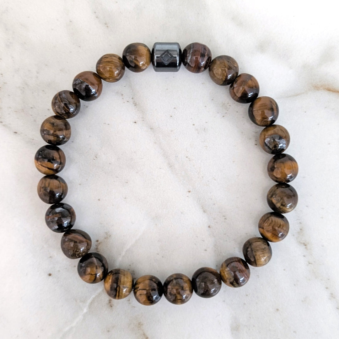 A 8mm beaded men's tiger's eye stretch bracelet with a single hematite Lapis London logo bead.