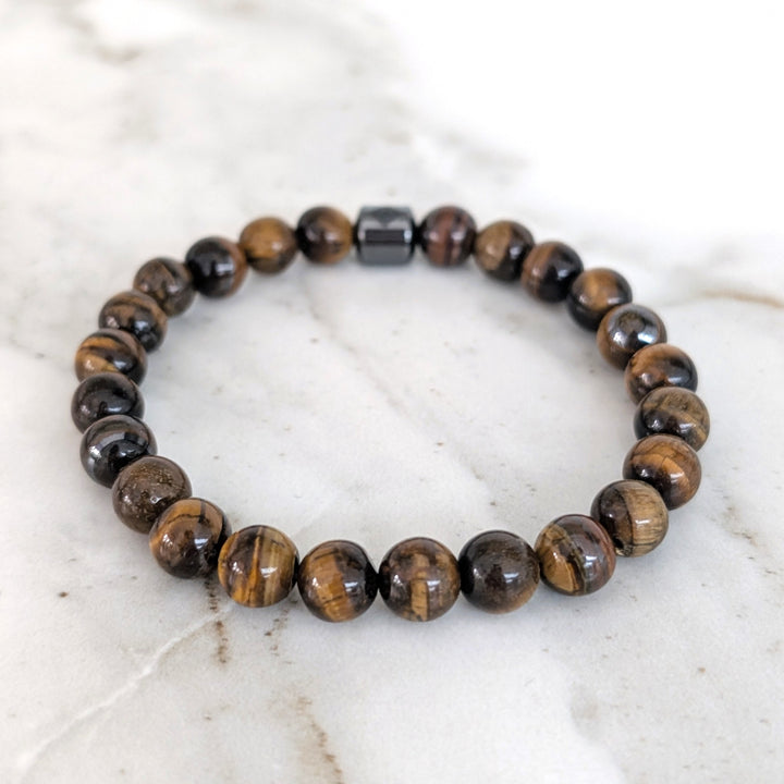 A 8mm beaded men's tiger's eye stretch bracelet with a single hematite Lapis London logo bead.