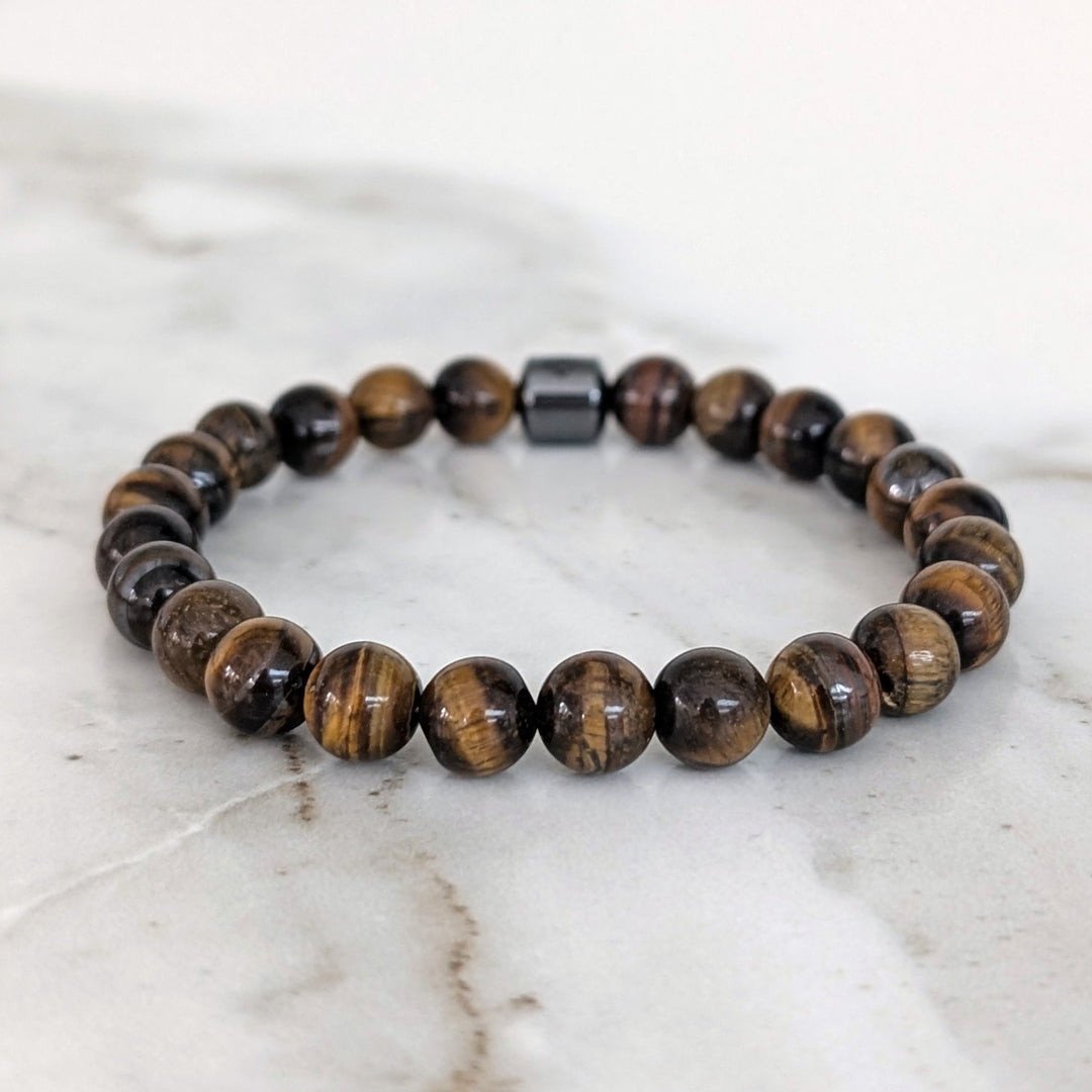 A 8mm beaded men's tiger's eye stretch bracelet with a single hematite Lapis London logo bead.