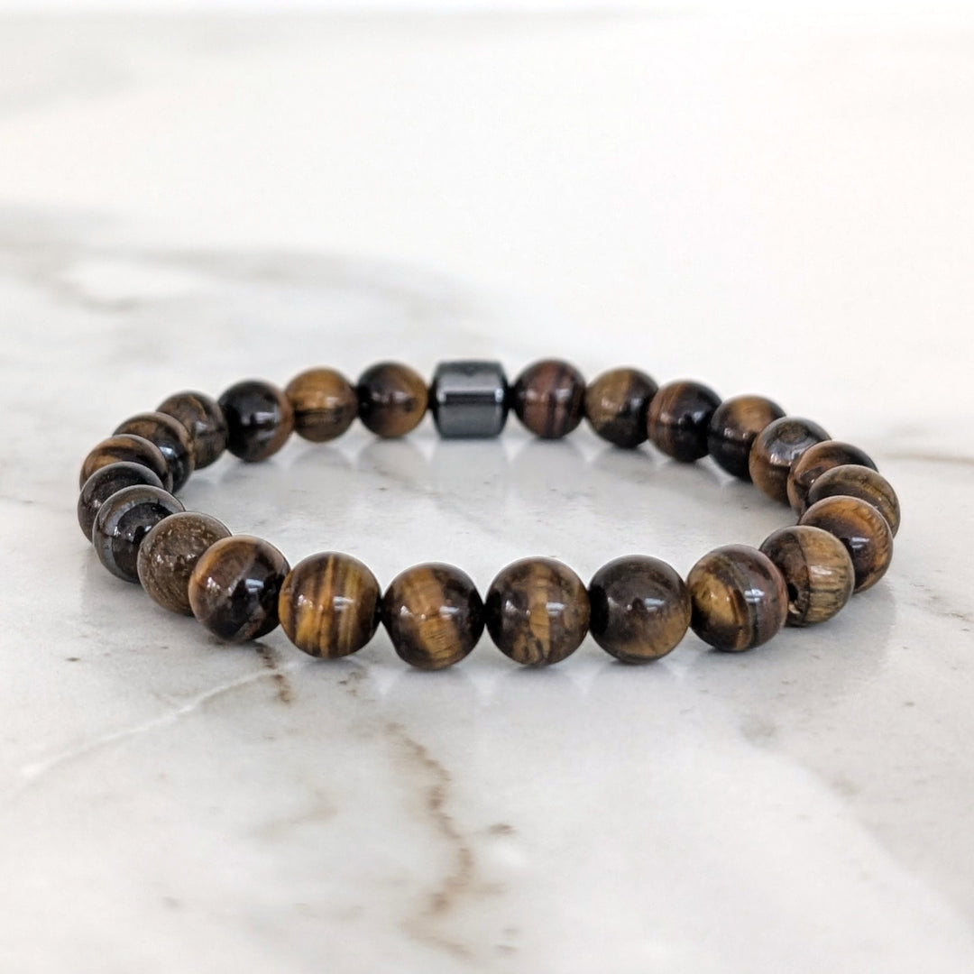 A 8mm beaded men's tiger's eye stretch bracelet with a single hematite Lapis London logo bead.