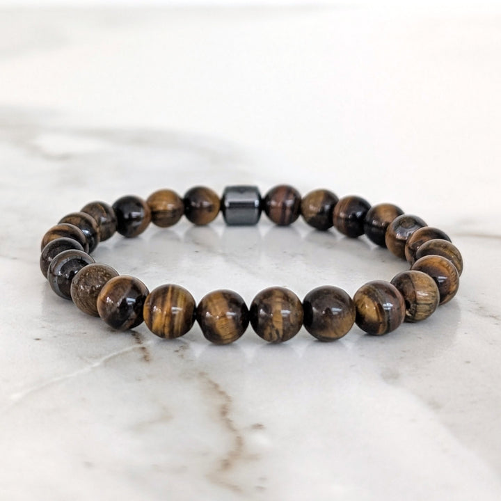 A 8mm beaded men's tiger's eye stretch bracelet with a single hematite Lapis London logo bead.