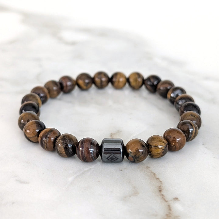 A 8mm beaded men's tiger's eye stretch bracelet with a single hematite Lapis London logo bead.