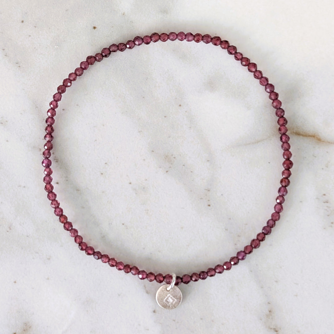 Garnet 2mm beaded bracelet with a silver charm 