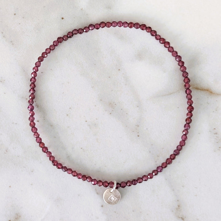 Garnet 2mm beaded bracelet with a silver charm 