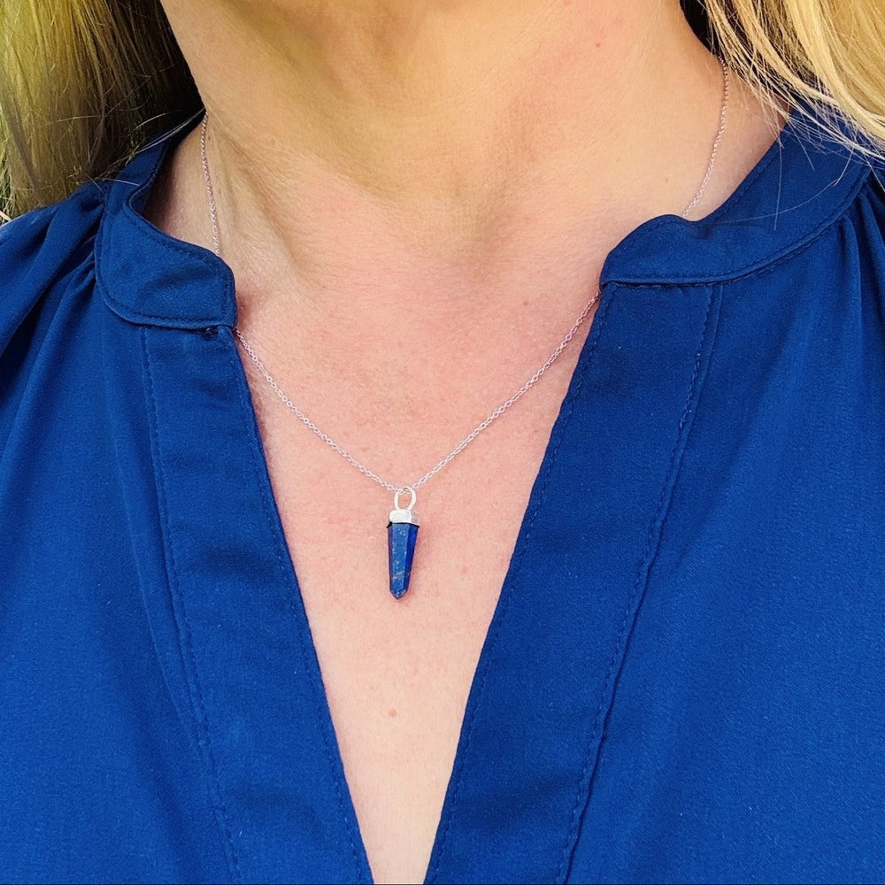 Blue lapis lazuli pendant gemstone necklace on a stone surface