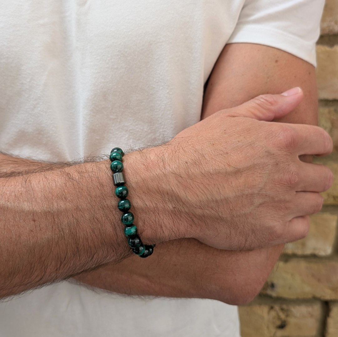 A men's 8mm beaded stretch bracelet made of polished dark green malachite beads with a single dark metallic hematite bead.