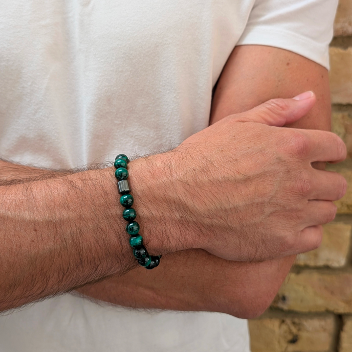 A men's 8mm beaded stretch bracelet made of polished dark green malachite beads with a single dark metallic hematite bead.