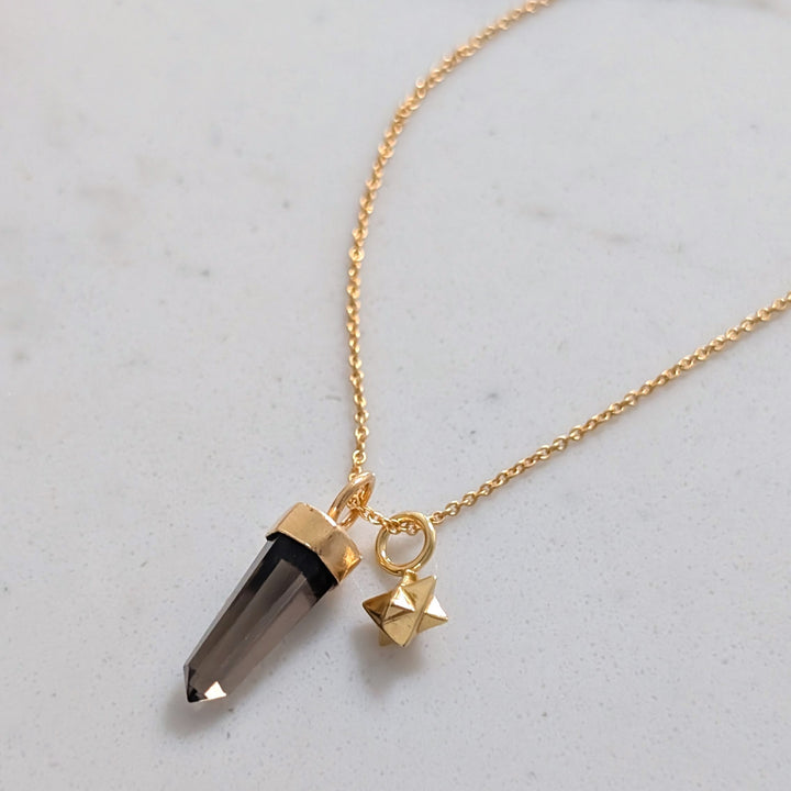 Gold necklace with a smoky quartz spike pendant and tetrahedron star charm
